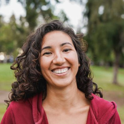 Portrait of native american woman smiling on camera with city park in background - Indigenous girl outdoor